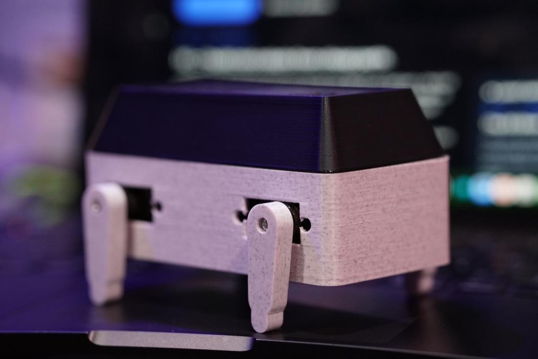 3D-printed walker robot with servo-driven legs standing on the workbench